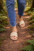 Person wearing sandals and blue jeans walking on a forest path