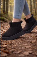 Black ankle boots worn on a forest floor with blurred background