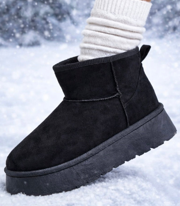 Black suede ankle boot on a snowy background