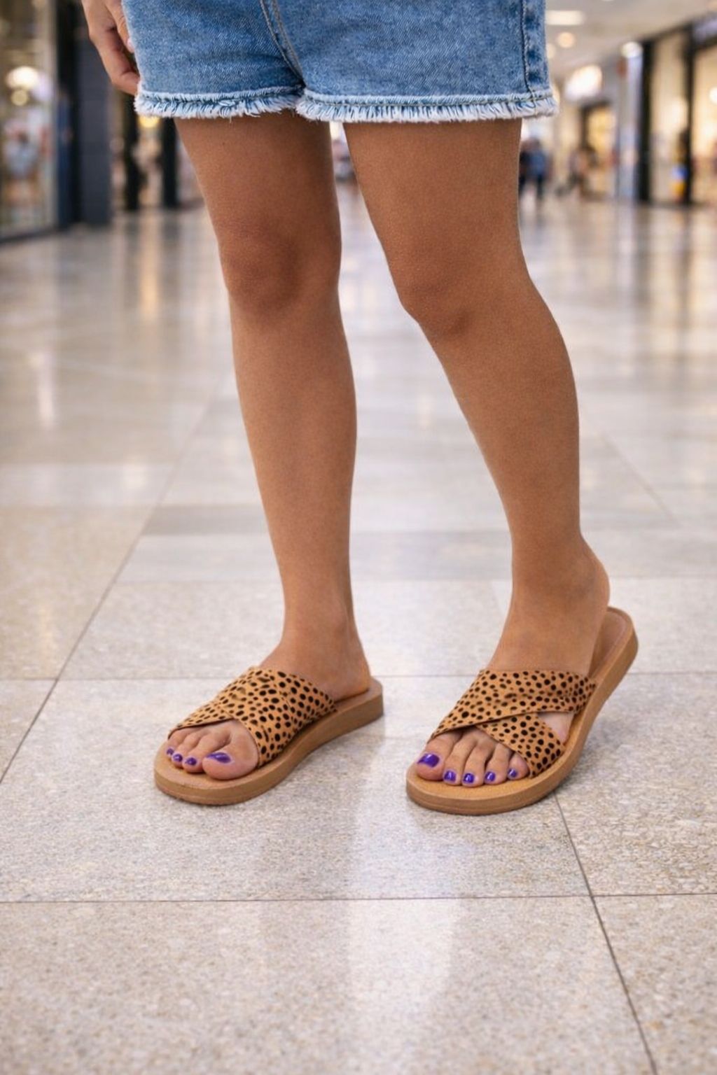 Person wearing leopard print sandals on a tiled floor
