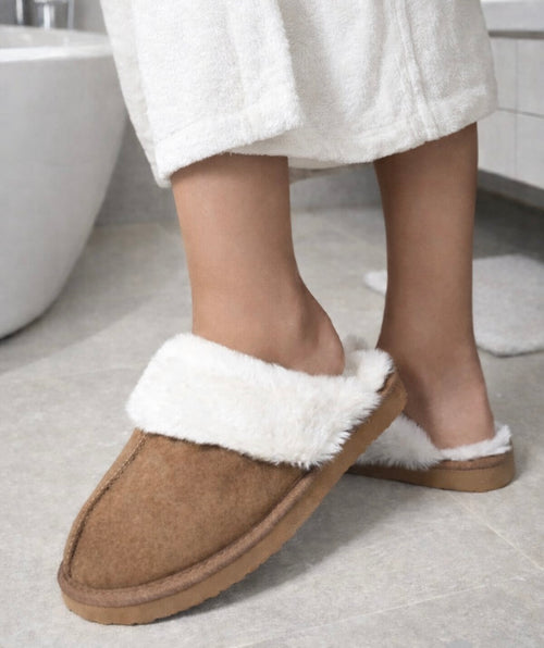 Person wearing brown slippers with white fur trim in a bathroom setting